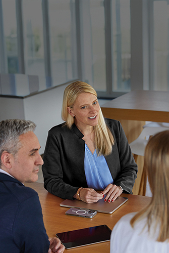 Drie leden van het Sales & Business Development-team van Apple die in een gemeenschappelijke ruimte aan een tafel zitten te praten.