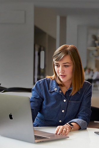Iemand van het Support & Service-team van Apple die in een gemeenschappelijke ruimte op een MacBook aan het werken is.