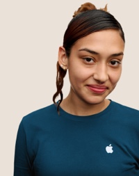 Portrait of a smiling Apple Retail team member with long dark hair with pink highlights.