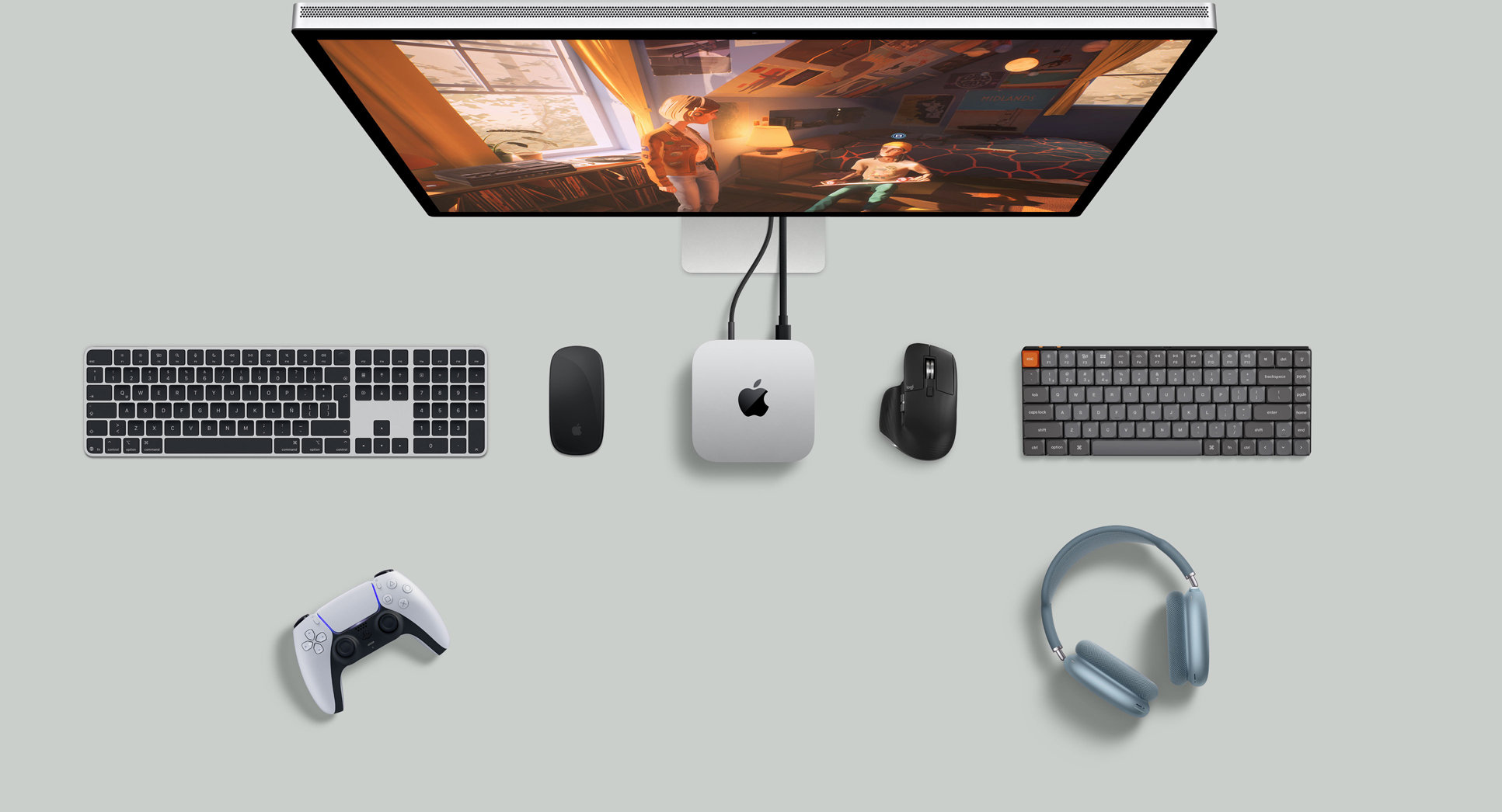 Vista desde arriba de una Mac mini color plata sobre un escritorio, con un monitor Studio Display, teclados inalámbricos, mouse inalámbricos, control para jugar y AirPods Max