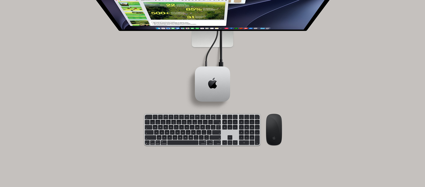 Mac mini, top, silver aluminum, rounded corners, glossy black Apple logo centered, connected by cord, Studio Display partially visible on top with screen showing Calendar app, Keynote presentation, and bar graph open, Magic Keyboard with Numeric Keypad, Magic Mouse visible below Mac mini