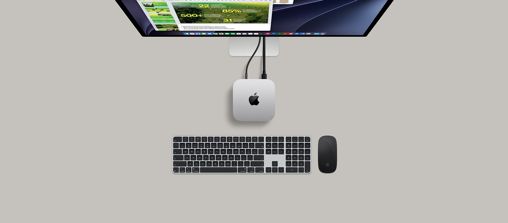 Mac mini, atas, aluminium perak, sudut melengkung, logo Apple hitam mengilap di tengah, terhubung dengan kabel, Studio Display sebagian terlihat dari atas, AirPods 4, terbuka, sampel warna Pantone, serta keyboard dan mouse Logitech merah