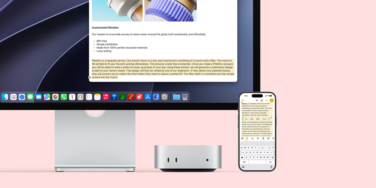 Mac mini front, tucked under Studio Display, an iPhone sits to the right of the device and the display, text selected with cut, copy, paste, and AutoFill commands above on iPhone matches highlighted text on display, showcasing Universal Clipboard