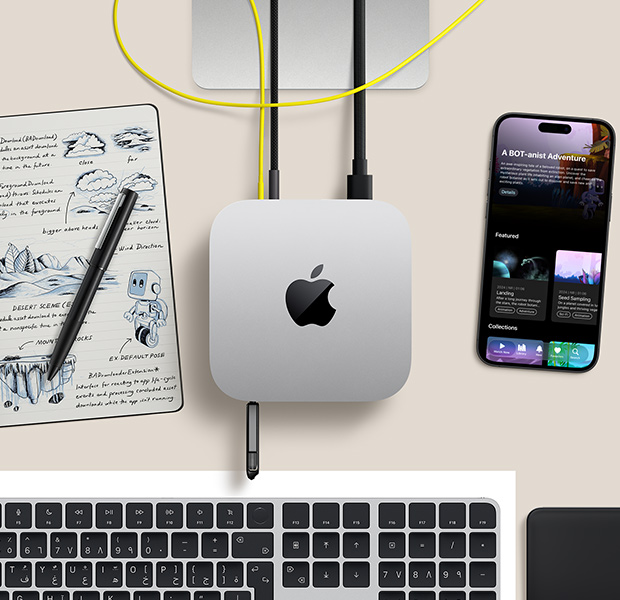 جهاز Mac mini، الجهة العلوية، ألومنيوم فضي، زوايا مدورة، شعار Apple باللون الأسود اللامع في الوسط، متصل بسلك، وحدة تخزين USB موضوعة في منفذ USB‑C في الجهة الأمامية، قاعدة شاشة 
Studio Display تظهر بشكل جزئي، جهاز iPhone، لوحة تعقب ماجيك، لوحة مفاتيح ماجيك مع ميزة بصمة الإصبع، قلم إلكتروني ولوحة رسم بالحبر الإلكتروني