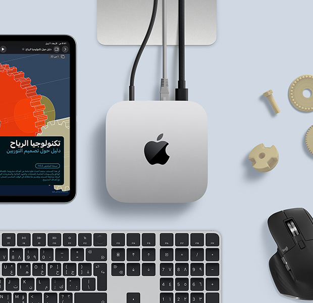 جهاز iPad يعرض عناصر STEM مفصلة، جهاز Mac mini في الوسط مع كابل طاقة متصل به، قاعدة شاشة Studio Display تظهر بشكل جزئي، متصلة عبر USB‑C، لوحة مفاتيح ماجيك مع ميزة بصمة الإصبع، وماوس من Logitech‏