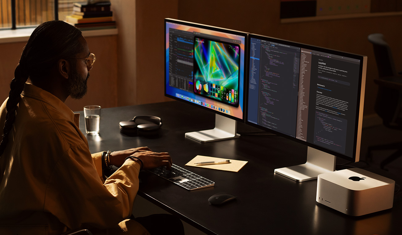 A professional working with Mac&nbsp;Studio and two Studio&nbsp;Display monitors