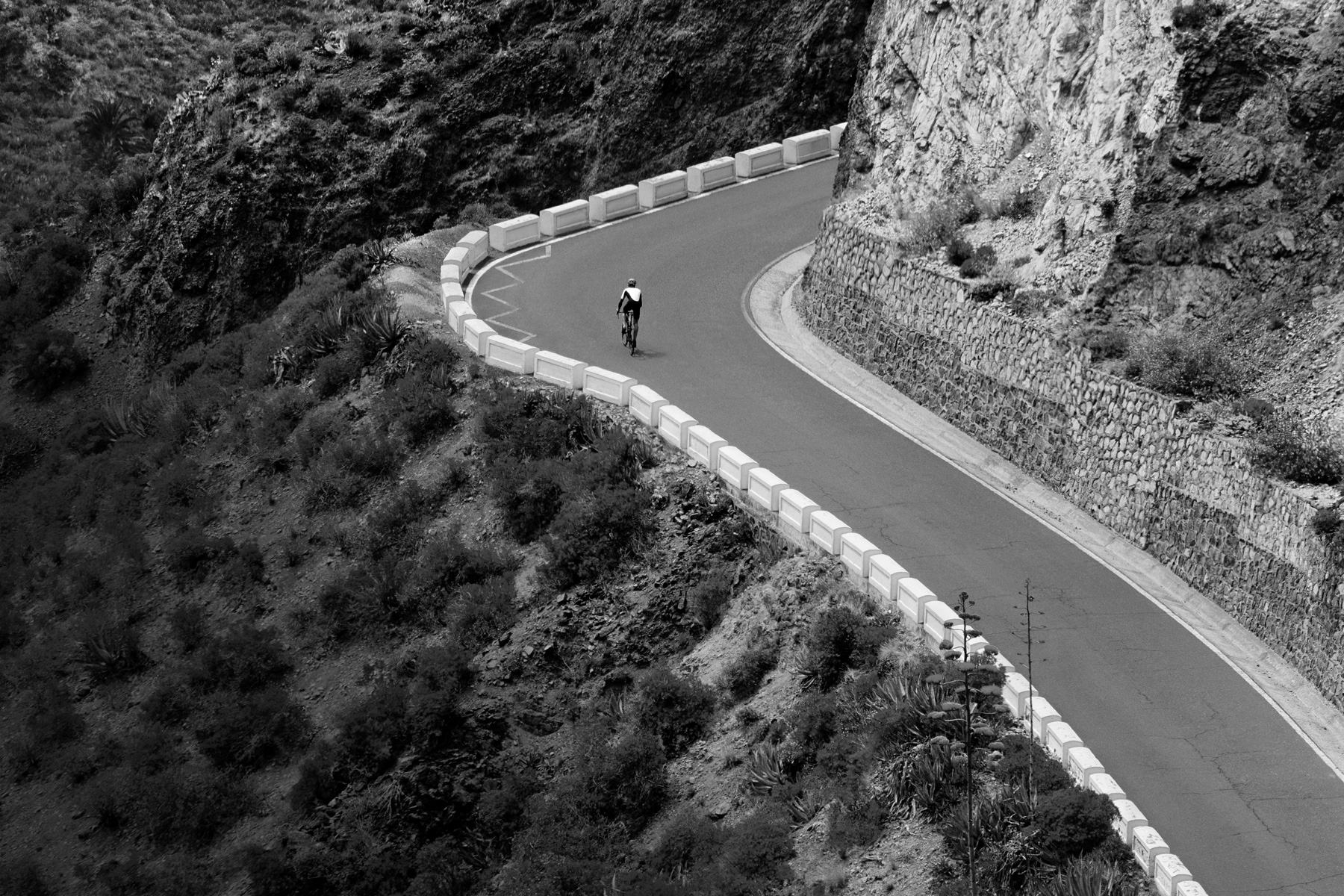 Eine Person fährt mit dem Rad eine Gebirgsstrasse hinauf