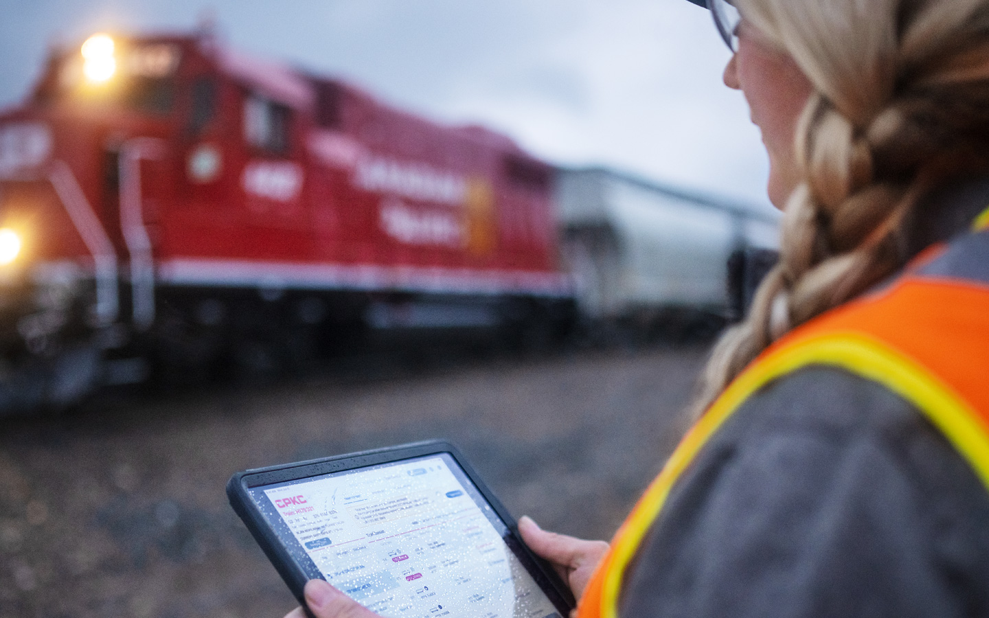 Een spoorwegmedewerkster beoordeelt treinschema’s op iPad terwijl zij op het treinstation staat